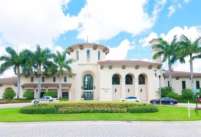 a view of a white building among the street with palm trees