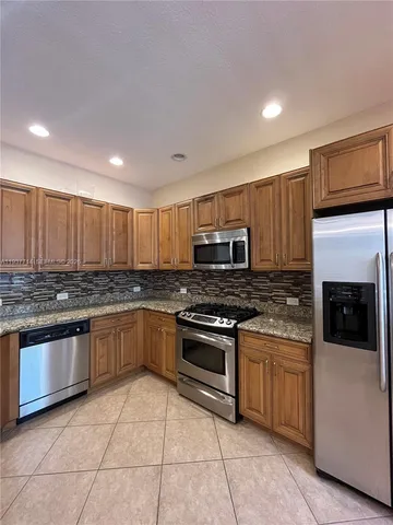 a large kitchen with stainless steel appliances granite countertop a stove and a sink