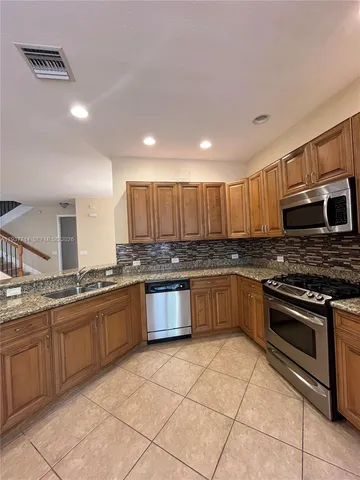 a large kitchen with stainless steel appliances granite countertop a stove granite counter tops and white cabinets