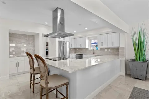 a kitchen with stainless steel appliances granite countertop a sink a stove a refrigerator with white cabinets and wooden floor