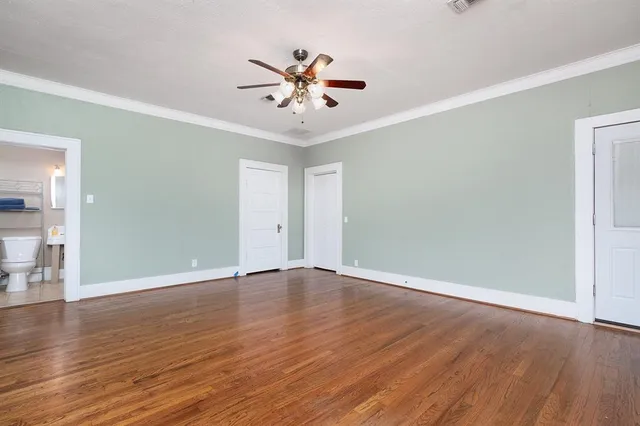 an empty room with wooden floor chandelier fan and windows