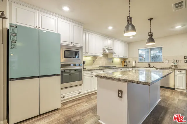 a kitchen with kitchen island granite countertop a sink appliances cabinets and counter space