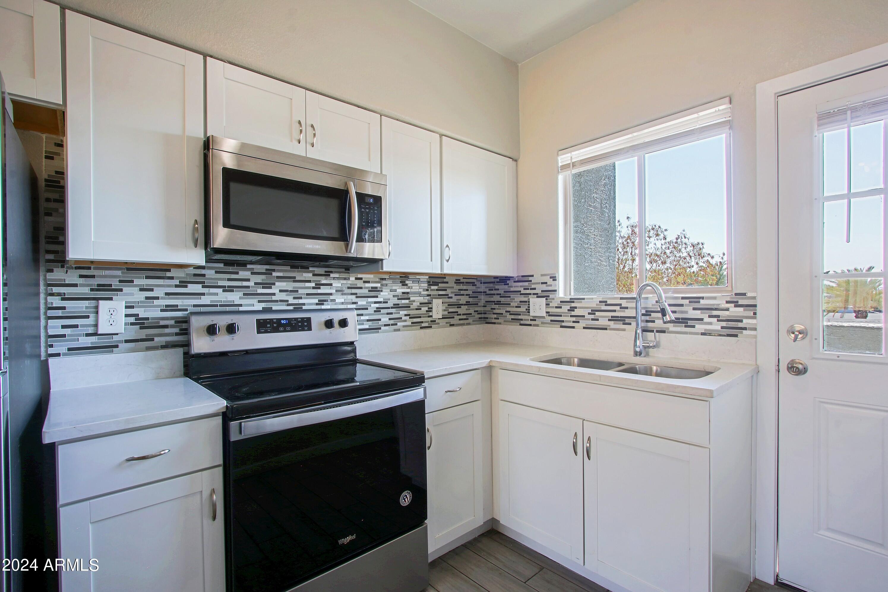 1614 West Purdue Avenue, Unit 202 Phoenix, AZ 85021 - Photo 2 of 8 a kitchen with cabinets stainless steel appliances a sink and a window
