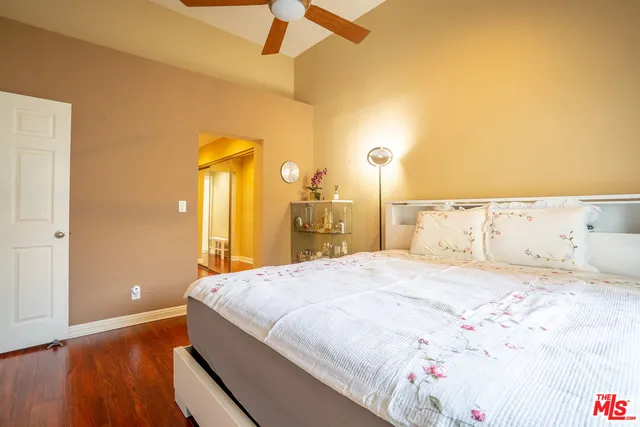 a bedroom with a bed and a dresser with wooden floor