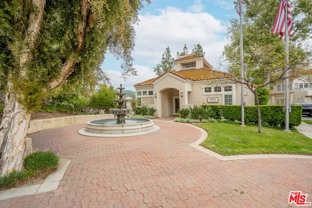 a view of a white house with a big yard plants and large trees