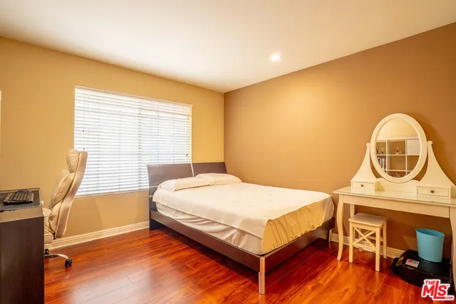 a bedroom with a bed a dresser next to a window