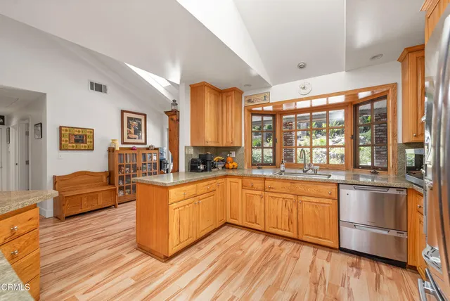 a kitchen with stainless steel appliances granite countertop a refrigerator a stove and a sink with wooden floor