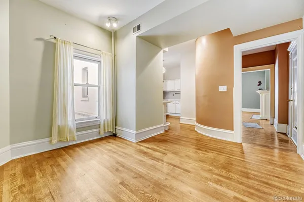 a view of an empty room with wooden floor and a window