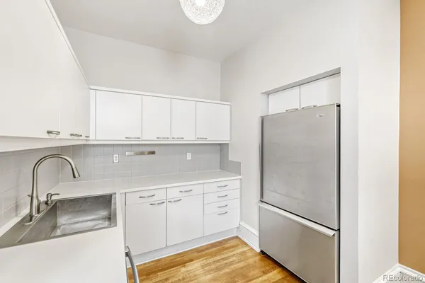 a kitchen with white cabinets and refrigerator