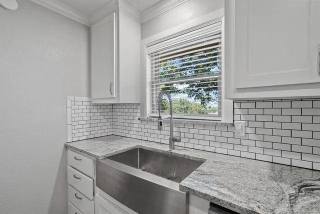a kitchen with granite countertop white cabinets and a sink