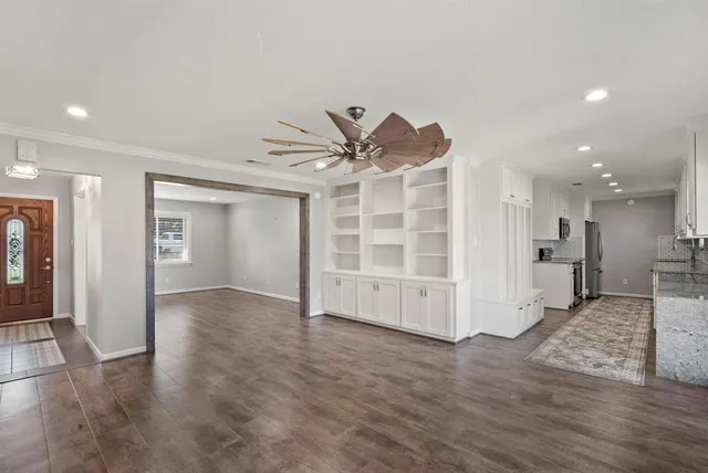 an empty room with wooden floor and a ceiling fan