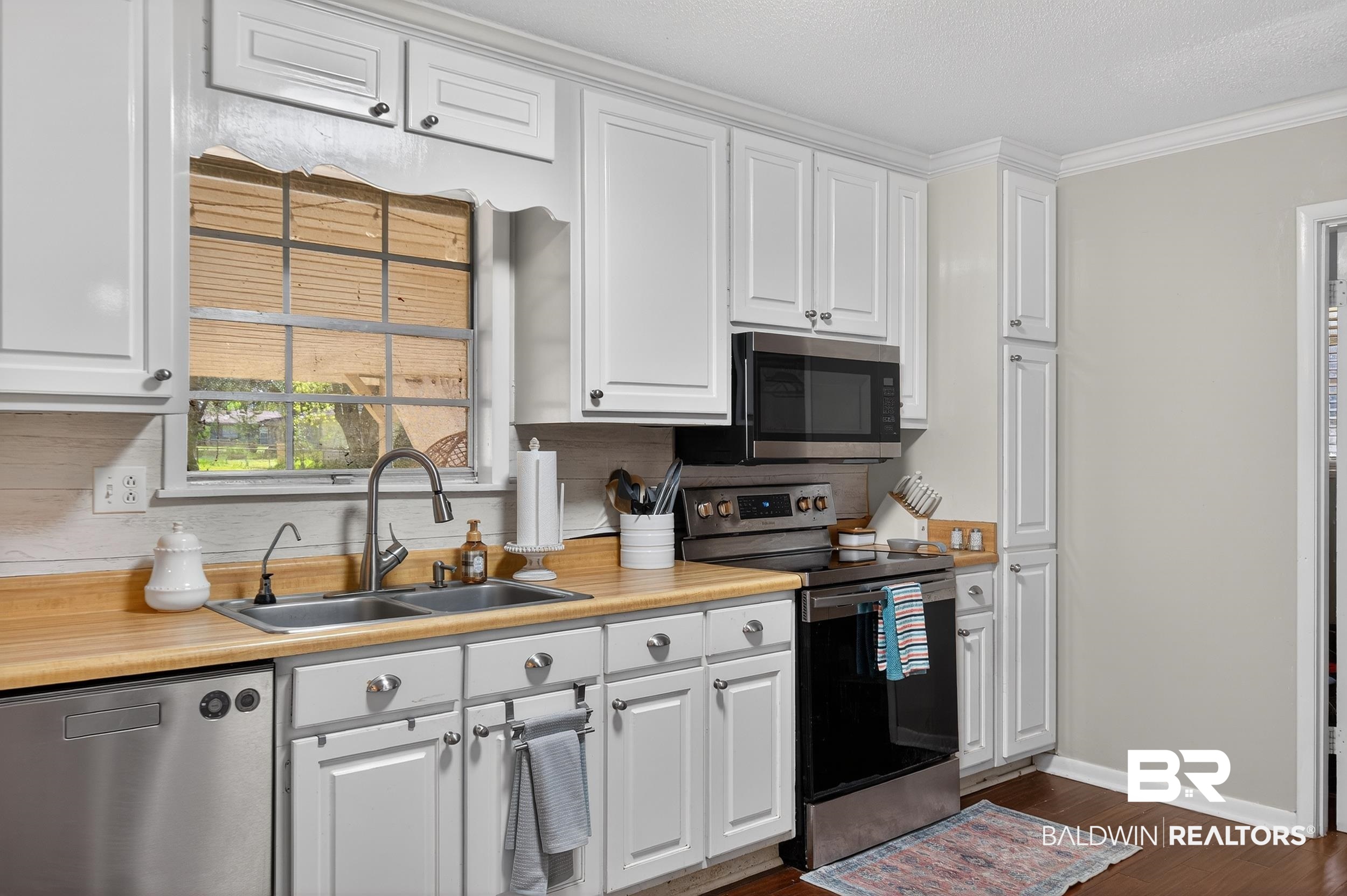 46006 Pecan Lane Bay Minette, AL 36507 - Photo 16 of 40 Kitchen featuring stainless steel appliances, light countertops, white cabinets, dark wood-type flooring, and crown molding