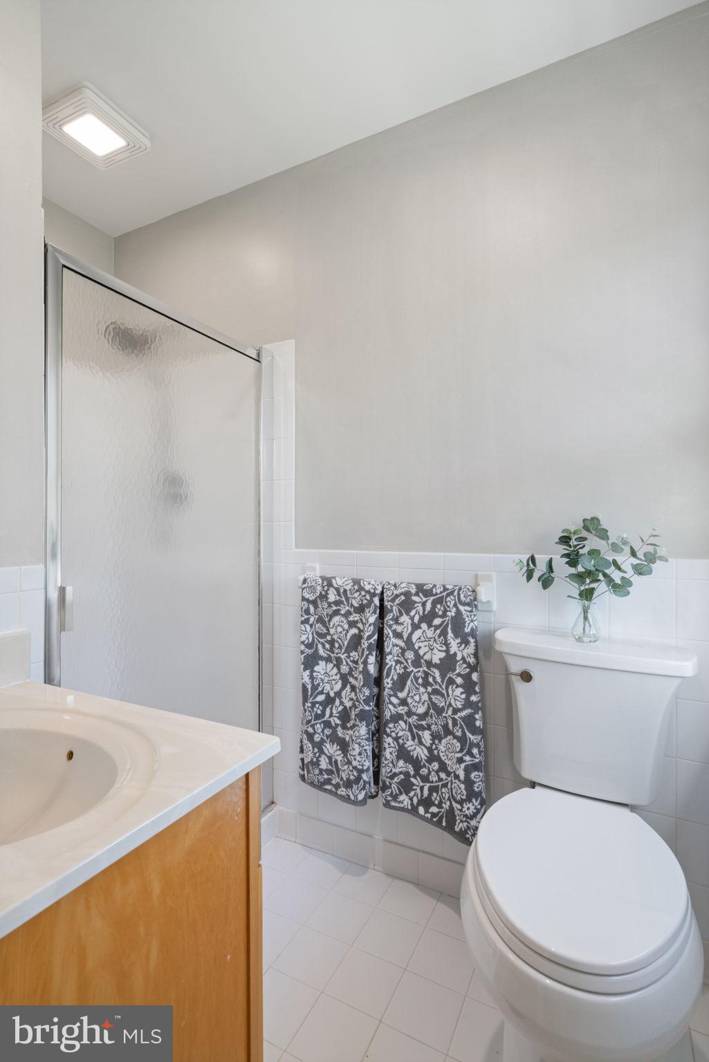 8328 Carrleigh Parkway Springfield, VA 22152 - Photo 27 of 58 a bathroom with a granite countertop toilet a sink and a shower