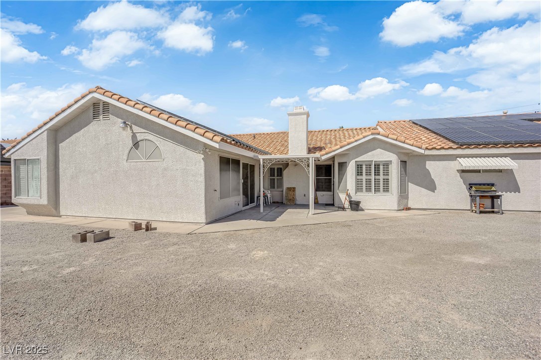 1637 East Robindale Road Las Vegas, NV 89123 - Photo 36 of 45 Back of house featuring stucco siding, solar panels, a chimney, and a tiled roof