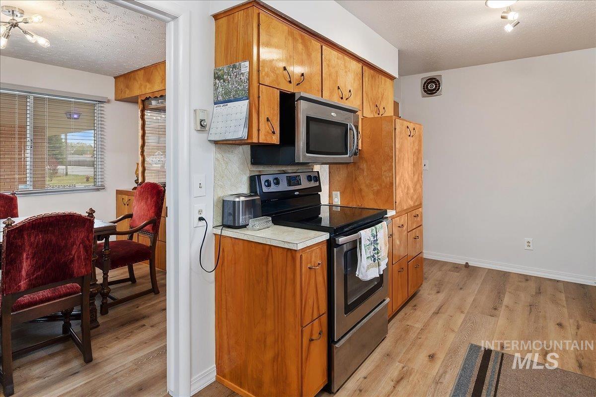 2012 21st Street Heyburn, ID 83336 - Photo 17 of 38 Kitchen with stainless steel appliances, a textured ceiling, light wood-style flooring, wood finish cabinets, and light countertops
