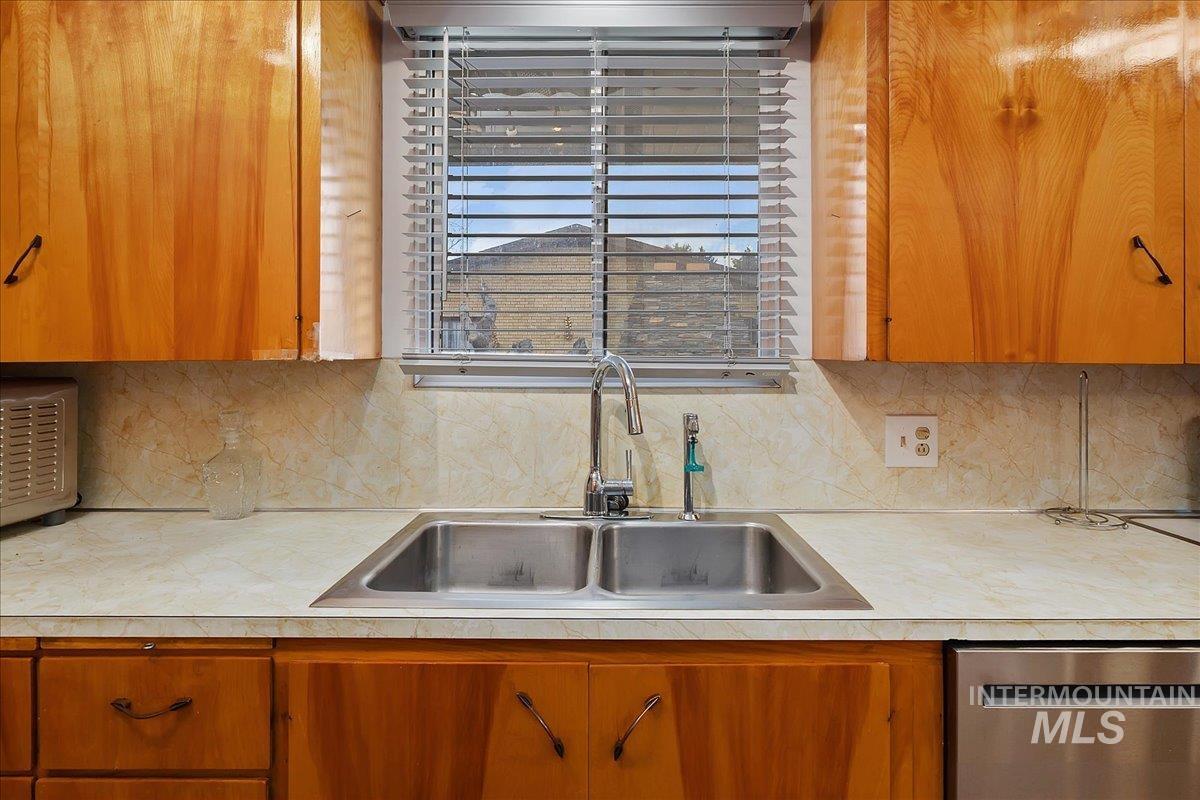 2012 21st Street Heyburn, ID 83336 - Photo 19 of 38 Kitchen featuring wood finish cabinets, dishwasher, light countertops, and backsplash
