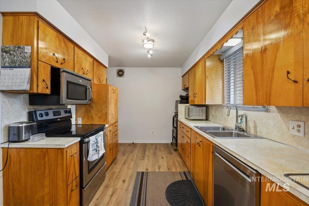2012 21st Street Heyburn, ID 83336 - Photo 20 of 38 Kitchen with stainless steel appliances, tasteful backsplash, light countertops, light wood-style floors, and wood finish cabinetry