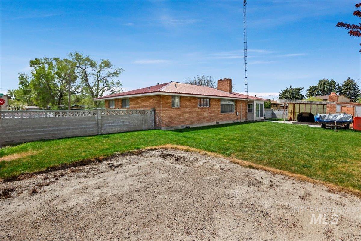 2012 21st Street Heyburn, ID 83336 - Photo 35 of 38 Back of property featuring a fenced backyard, a chimney, brick siding, a metal roof, and a patio