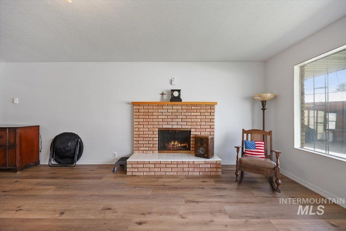 2012 21st Street Heyburn, ID 83336 - Photo 6 of 38 Living area featuring wood finished floors, a fireplace, and a textured ceiling