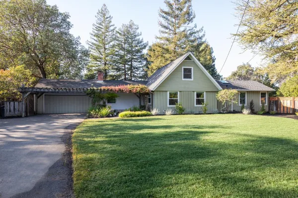 a front view of a house with a garden and trees