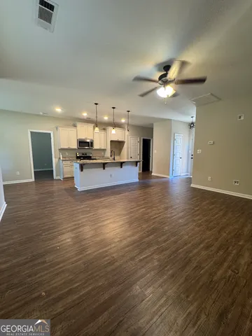 a view of a kitchen with kitchen island wooden floors appliances and a ceiling fan