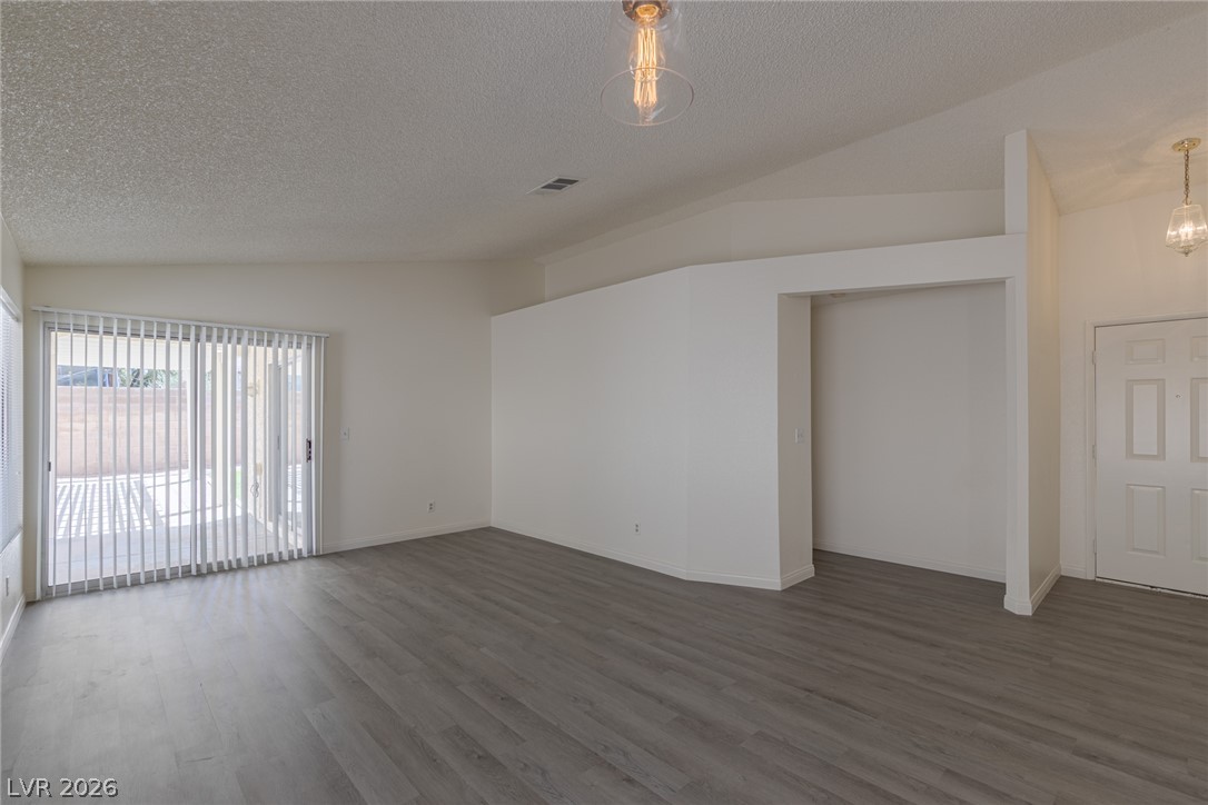 2803 Mirage Road Henderson, NV 89074 - Photo 9 of 39 An open living area features vaulted ceilings, durable wood-look flooring, and a sliding glass door.