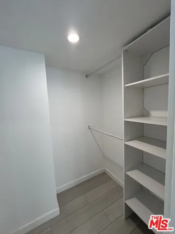 a view of an empty room with wooden floor and closet