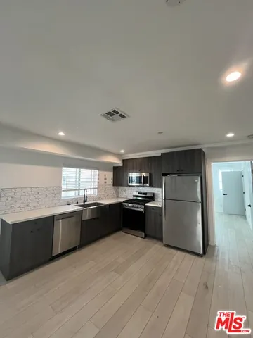 a large kitchen with granite countertop a stove top oven a sink dishwasher and a refrigerator