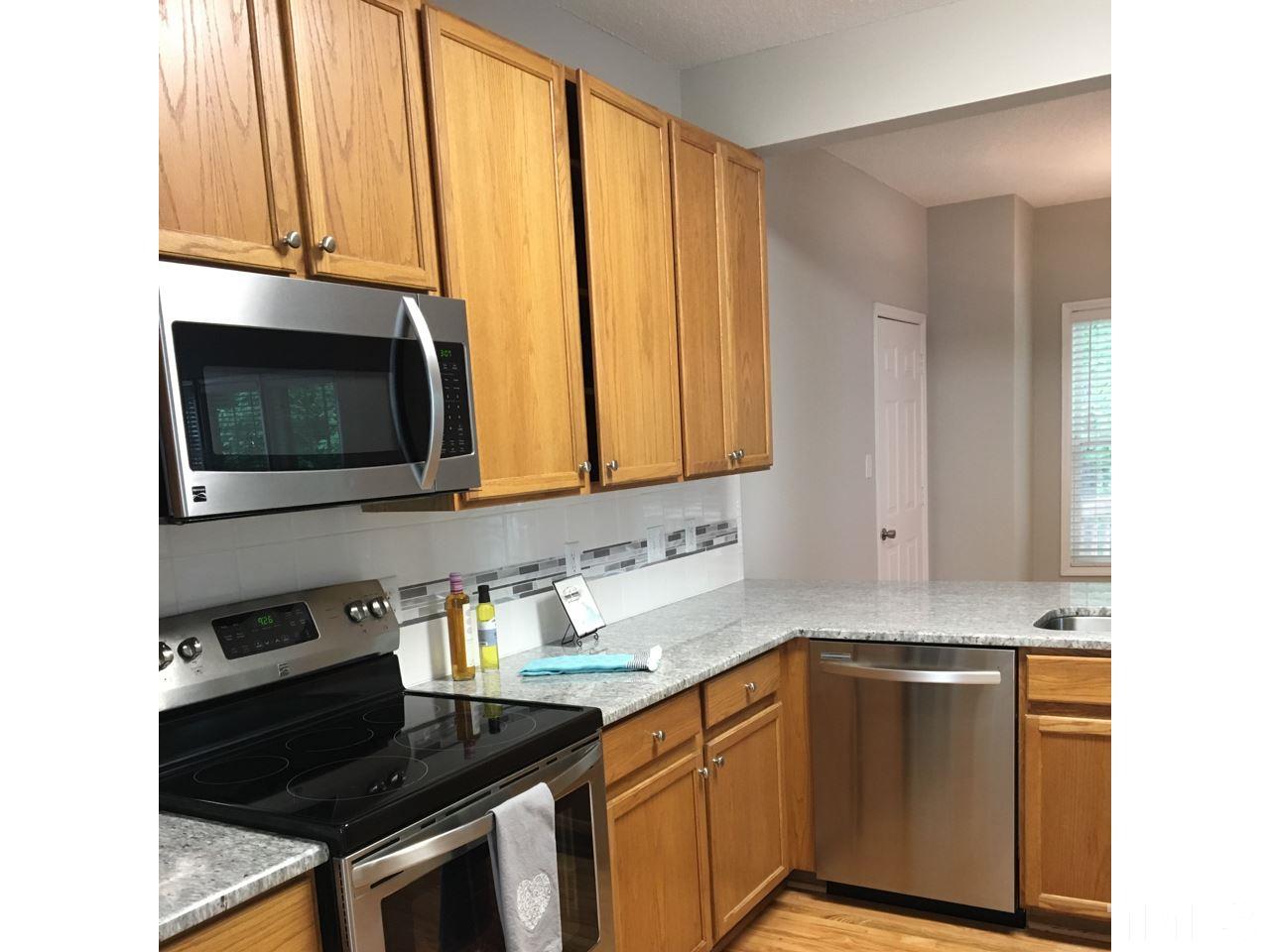 1410 Big Leaf Loop Apex, NC 27502 - Photo 3 of 20 a kitchen with stainless steel appliances a stove a microwave and sink