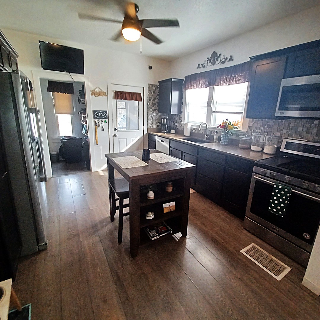 122 South Beach Street Kewanee, IL 61443 - Photo 28 of 49 a kitchen with stainless steel appliances granite countertop a refrigerator a sink dishwasher a stove and a dining table with wooden floor