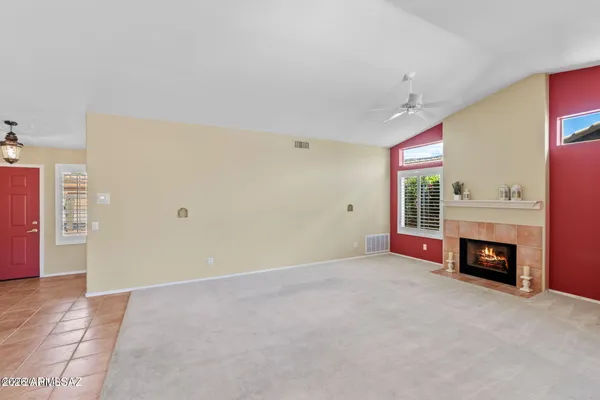 a view of an empty room with fire place and a kitchen