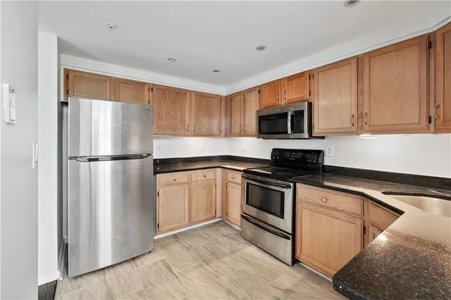 a kitchen with stainless steel appliances granite countertop a refrigerator stove a sink and a microwave