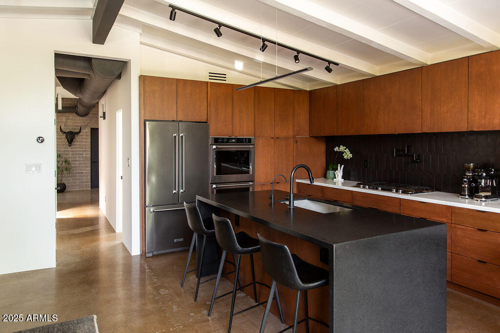 4032 North 45th Place Phoenix, AZ 85018 - Photo 9 of 38 a kitchen with stainless steel appliances a table chairs refrigerator and sink