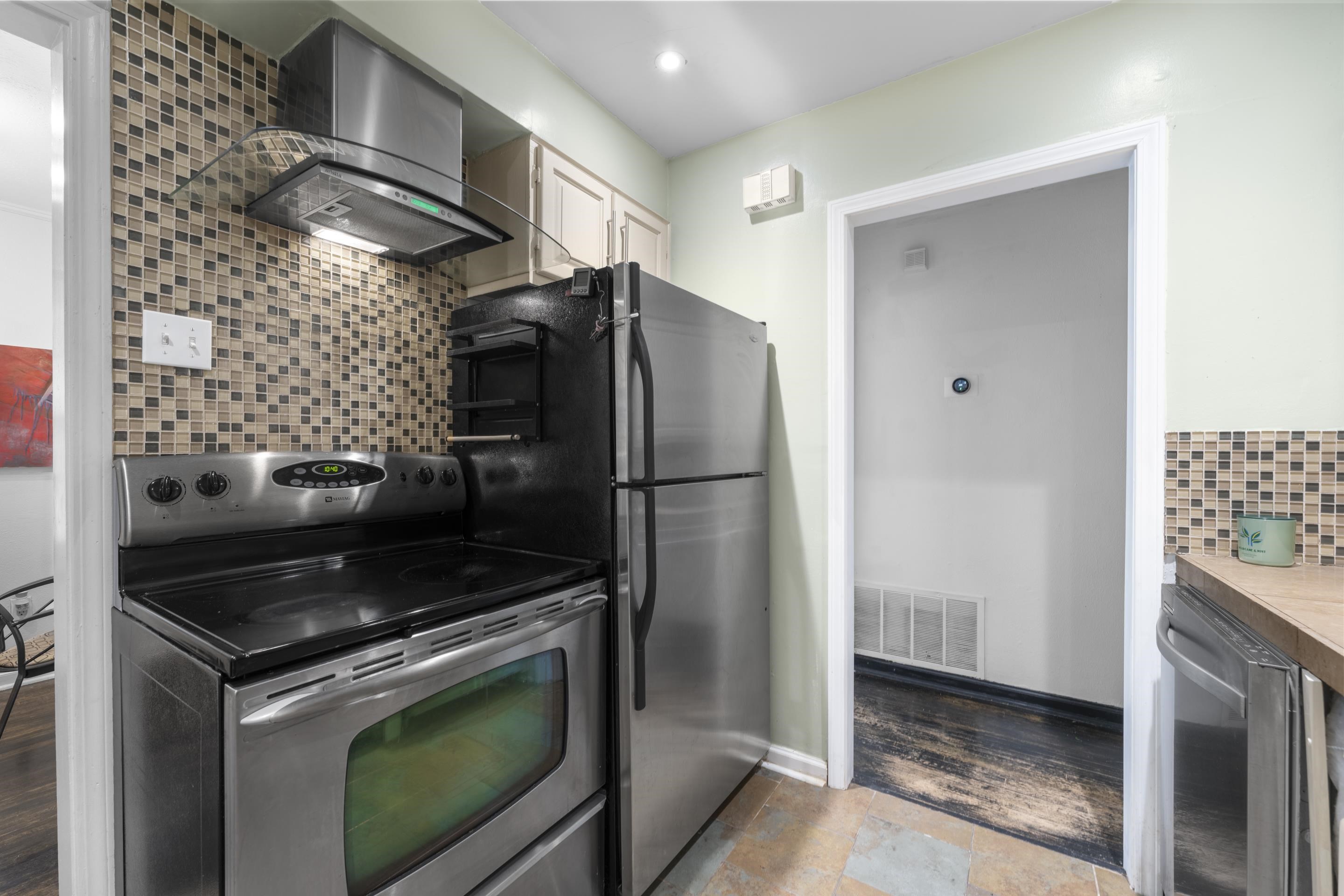 1343 Dearing Road Memphis, TN 38117 - Photo 8 of 19 Kitchen featuring stainless steel appliances, mosaic tile backsplash, a glass canopy range hood, light wood-finish cabinetry, and solid surface countertops
