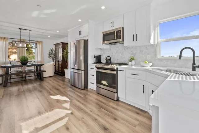 a kitchen with granite countertop a stove a sink dishwasher a refrigerator and a microwave oven with cabinets