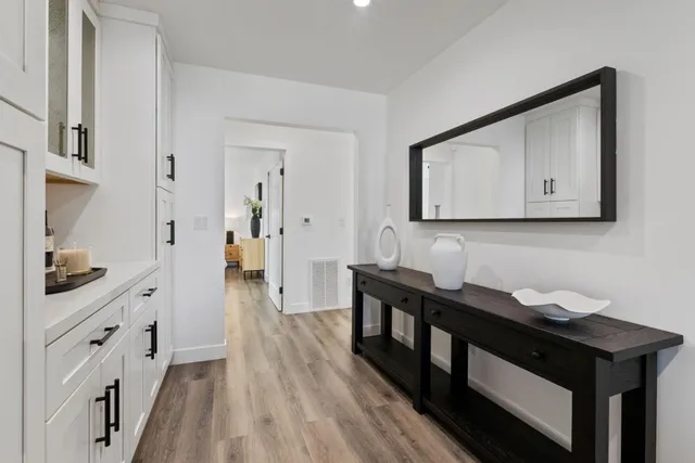 a hallway view with furniture a wooden floor and white cabinets