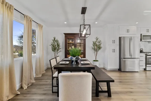 a kitchen with stainless steel appliances a dining table chairs and refrigerator