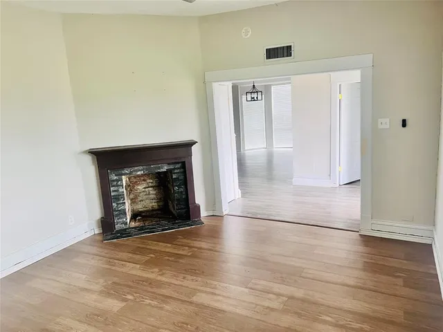 a view of an empty room with wooden floor and a fireplace