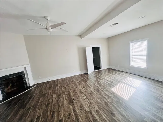 an empty room with wooden floor fireplace and windows