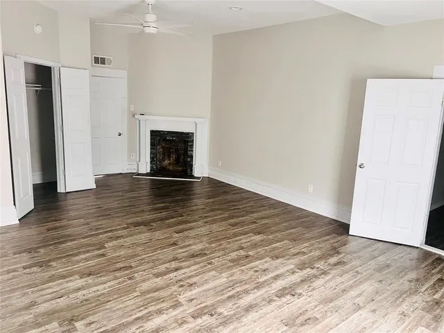 a view of an empty room with wooden floor and a fireplace