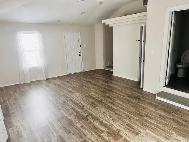 an empty room with wooden floor and a fireplace