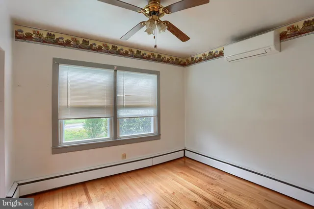 an empty room with wooden floor fan and windows