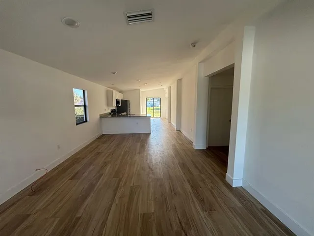 a view of a big room with wooden floor and windows