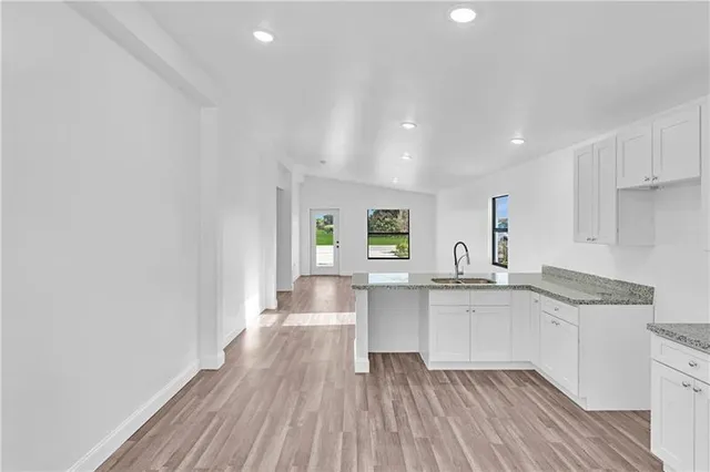 a kitchen with granite countertop a sink cabinets and wooden floor
