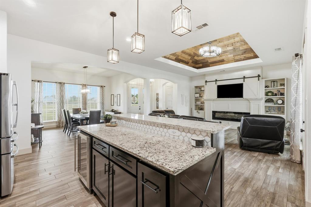 6020 Honeysuckle Road Midlothian, TX 76065 - Photo 11 of 39 Kitchen island featuring a granite countertop, hexagonal tile backsplash, and dark wood cabinetry