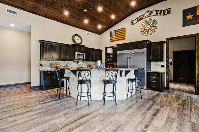 a kitchen with stainless steel appliances granite countertop a sink a stove and a wooden floors