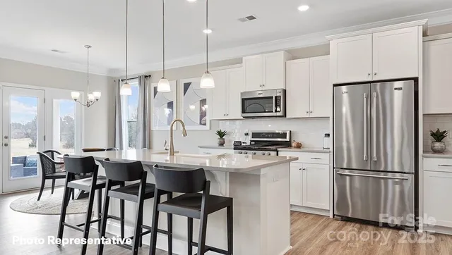 a kitchen with stainless steel appliances a dining table chairs refrigerator and microwave