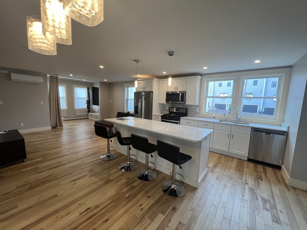 39 Snow Street, Unit 1 Boston, MA 02135 - Photo 11 of 35 a kitchen with stainless steel appliances a dining table chairs stove refrigerator and cabinets