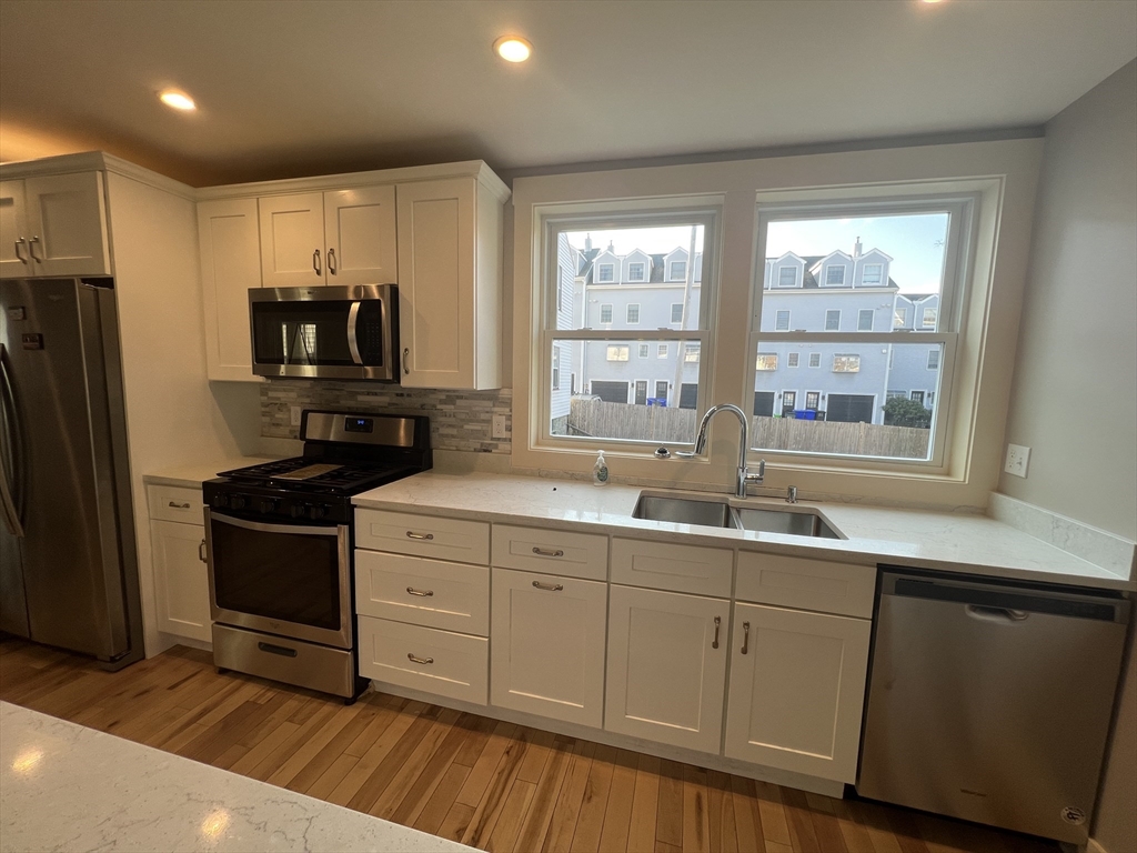 39 Snow Street, Unit 1 Boston, MA 02135 - Photo 12 of 35 a kitchen with stainless steel appliances a sink stove and refrigerator