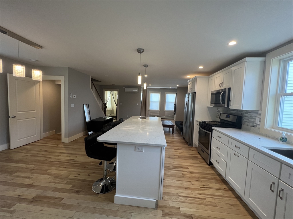 39 Snow Street, Unit 1 Boston, MA 02135 - Photo 15 of 35 a kitchen with stainless steel appliances kitchen island hardwood floor sink stove and wooden cabinets